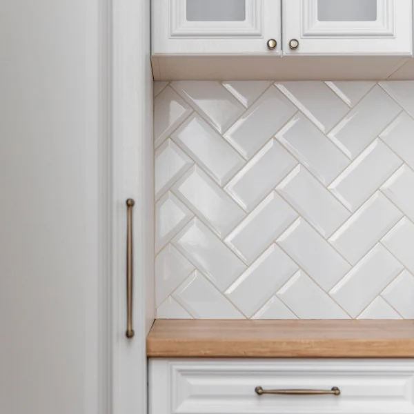 Cuisine blanche avec un dosseret en carrelage en chevrons, moderne et élégante.