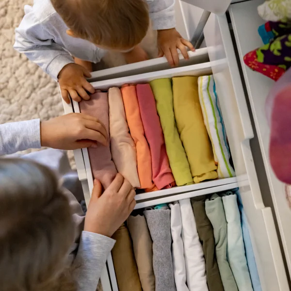 Deux enfants regardent un tiroir rempli de vêtements dans une garde-robe sur mesure.