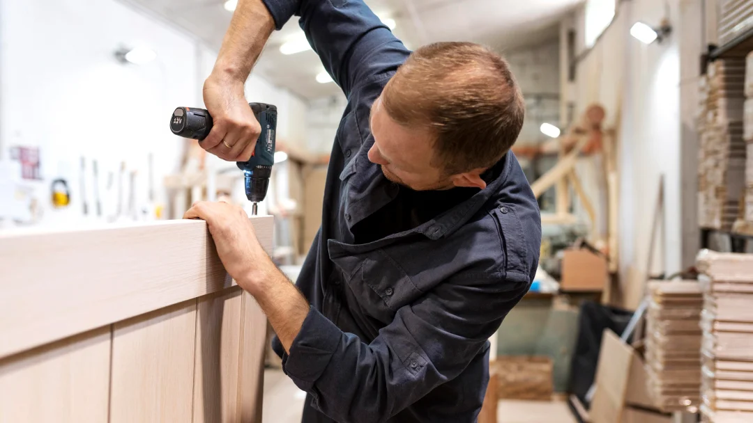 A man installs a wooden kitchen cabinet, focused on precise measurements and craftsmanship.